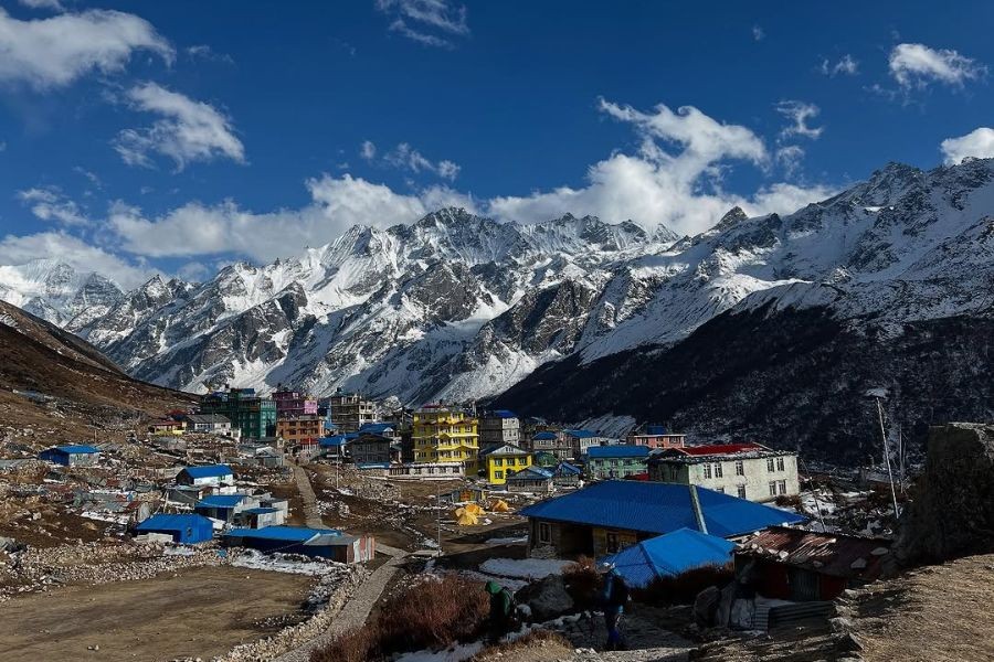 Mountain village with colorful buildings beneath snow-capped Himalayan peaks in Nepal